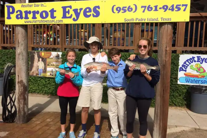 a group of people standing in front of a sign posing for the camera