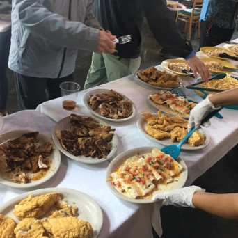 a group of people standing around a table with a plate of food