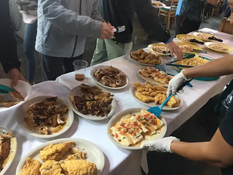 a group of people standing around a table with a plate of food